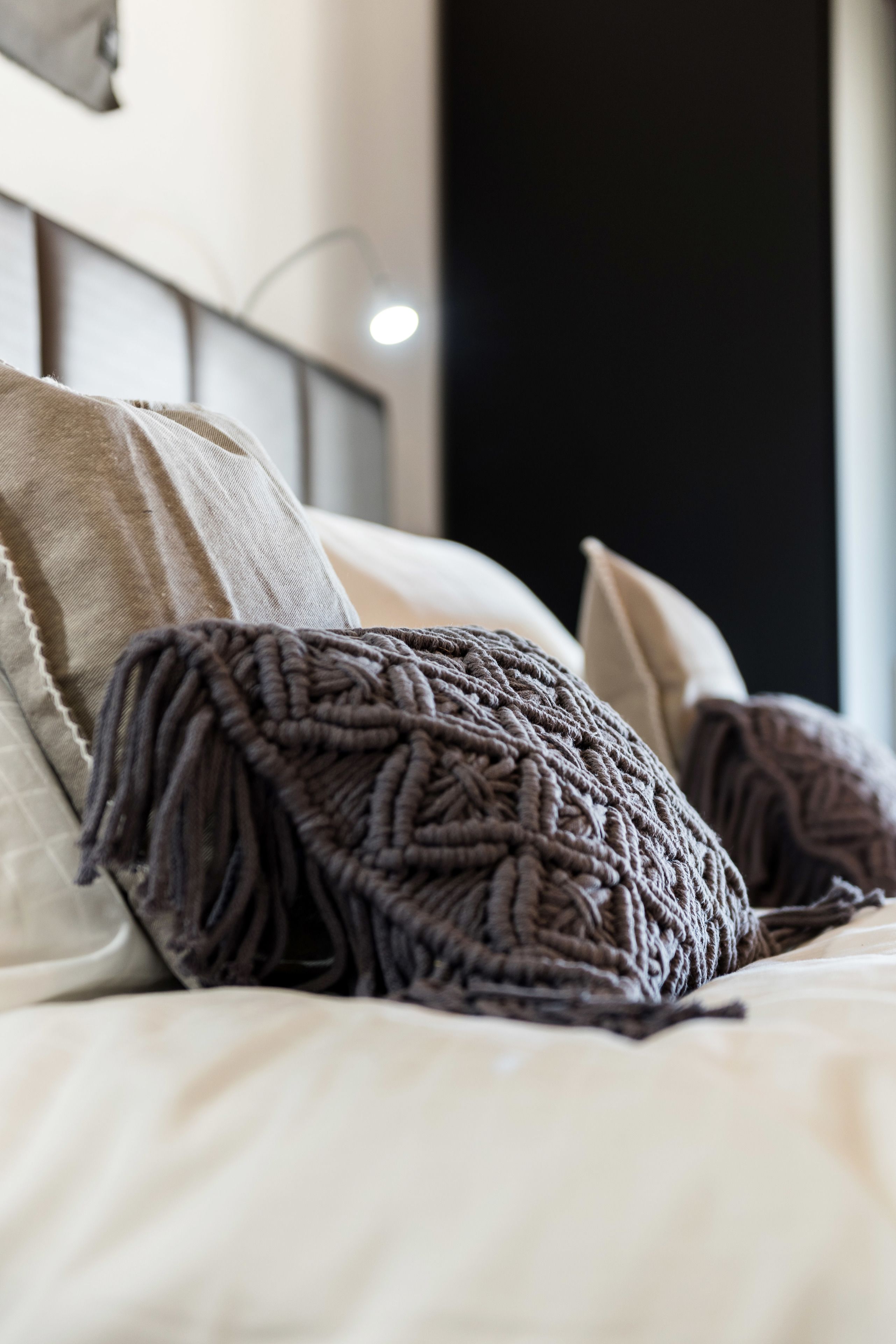 A bed with a knitted throw blanket and pillows.