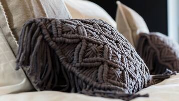 A bed with a knitted throw blanket and pillows.