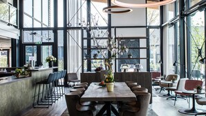 Un intérieur moderne avec une grande table à manger, de nombreuses chaises et un arrangement floral central.