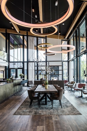 Un interior moderno con una amplia mesa de comedor, múltiples sillas y un arreglo floral central.
