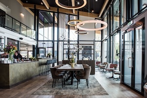 Un restaurante moderno con una mesa central, techos altos y ventanas amplias.