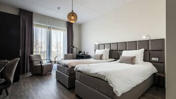 A modern hotel room with two beds, a desk, and a chair.