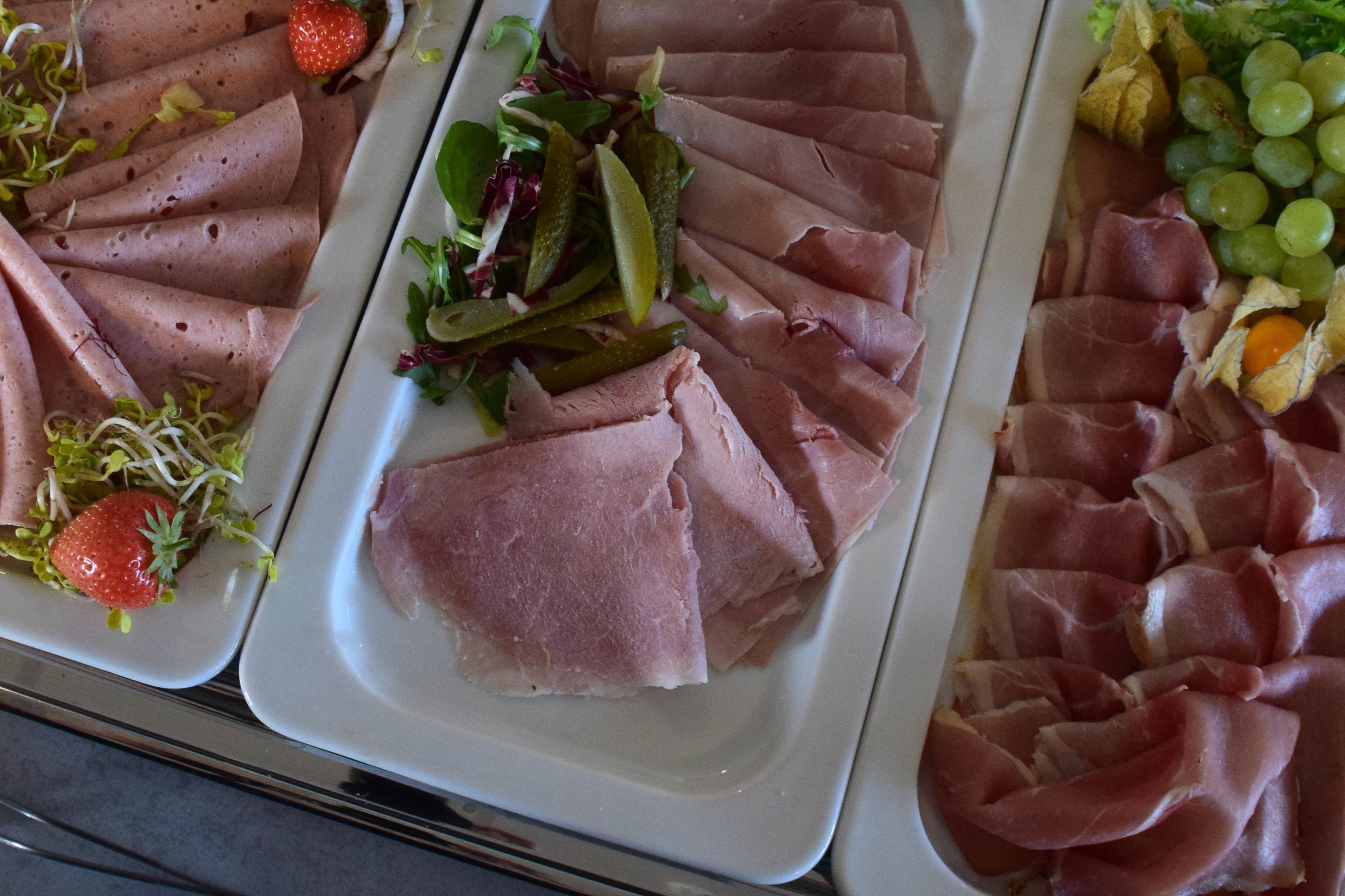 Un bufé con diversos alimentos, incluyendo carnes en rodajas, frutas y verduras.