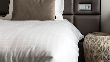 Una cama bien hecha con cabecera, lámpara de noche y reposapiés estampado.
