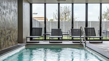 Una piscina techada, sillones reclinables de piscina