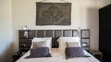 A double bed with two pillows, a bedside table with a lamp, and a wall-mounted artwork above the bed.
