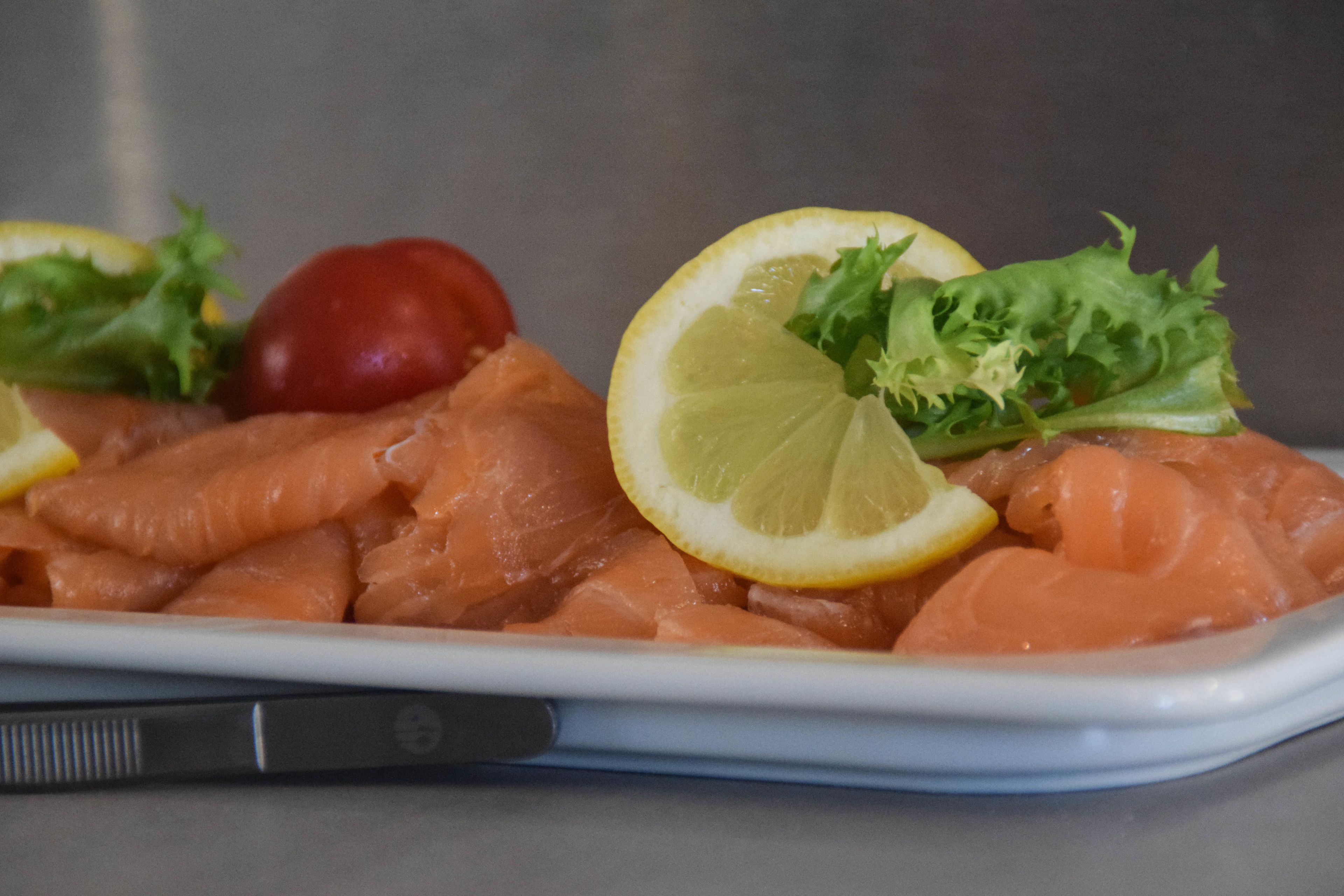 A tray of smoked salmon with lemon slices and lettuce.