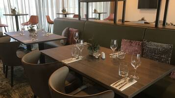 Un restaurant avec des tables en bois, des chaises rembourrées et un décor moderne comprenant un téléviseur et des lampes suspendues.