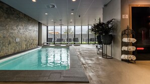 Piscina interior con vistas al exterior, zona de estar y toallas.