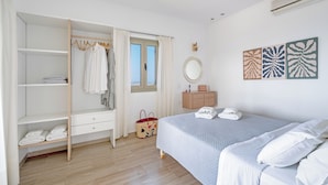 Een slaapkamer met een bed, een kledingkast, een kaptafel, een raam en kunst aan de muur.