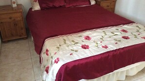A bed with a floral bedspread and two pillows, flanked by wooden nightstands with lamps. - 3 Bedroom Bungalow short & level walk to beach. Close to bus station and shops. (Puerto Rico de Gran Canaria)