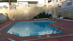 A rectangular swimming pool with a stone wall surrounding it, a white fence, and a staircase leading to an upper level. - 3 Bedroom Bungalow short & level walk to beach. Close to bus station and shops. (Puerto Rico de Gran Canaria)