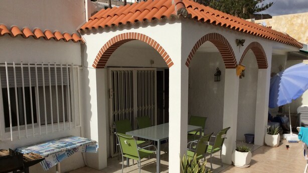 A patio area with a table and chairs, a potted plant, and a covered seating area. - 3 Bedroom Bungalow short & level walk to beach. Close to bus station and shops. (Puerto Rico de Gran Canaria)