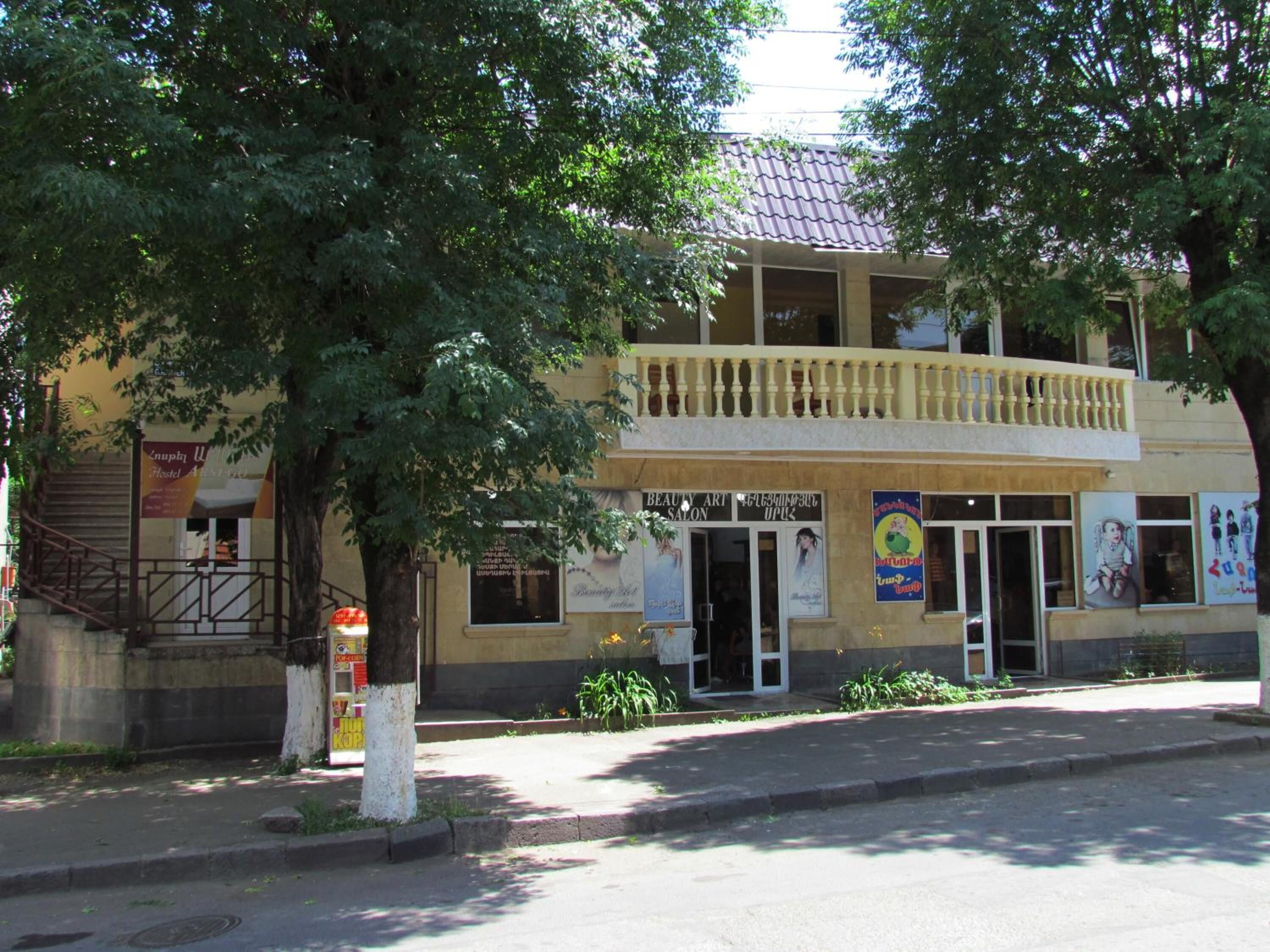 A two-story building with a balcony on the upper floor, a sign for a beauty salon, and a staircase leading to the entrance.