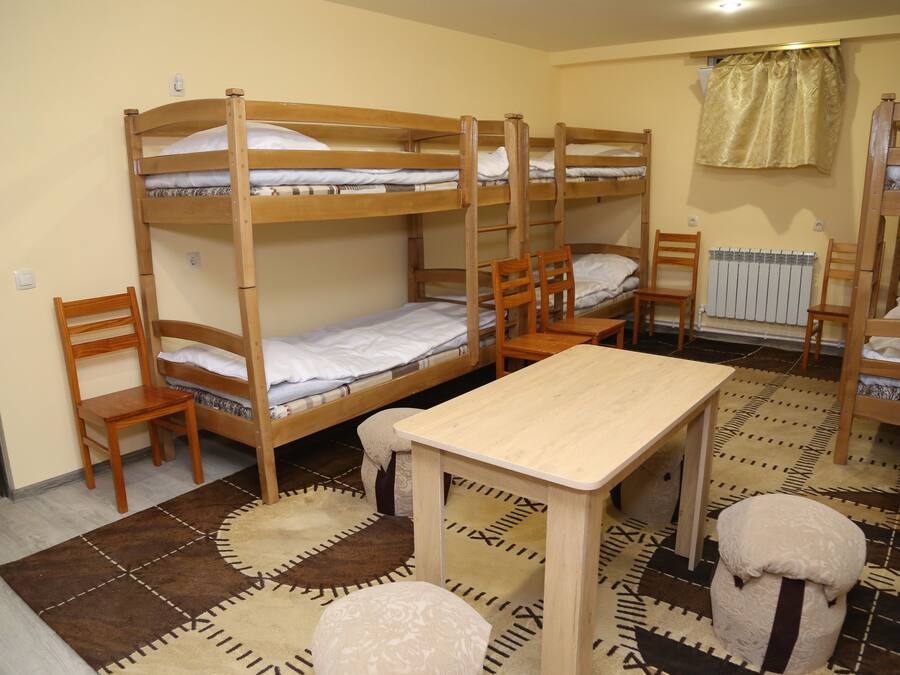 A bunk bed room with a wooden table and chairs.