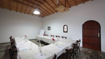 A conference room with long tables, chairs, a whiteboard, and a wooden door.