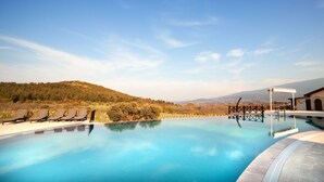 Una piscina con sillones de descanso y vistas a un paisaje montañoso.