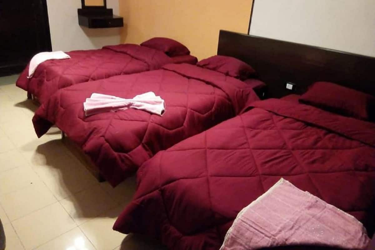 Ein Hotelzimmer mit zwei Betten, jeweils mit einer roten Bettdecke und einem weißen Kopfkissen.
