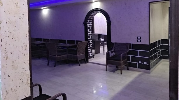 Una habitación de diseño moderno, con una zona de estar que incluye sillas y una pequeña mesa, un arco decorativo y suelo de baldosas.