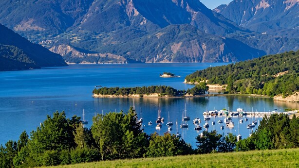A marina with boats, a lake, and mountains in the background.