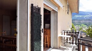 A building with a sign reading 'OLEVACANCES,' a balcony with outdoor furniture, and a view of a valley.