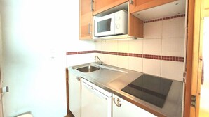 Cocina compacta con armarios de madera, microondas, pileta y lavavajillas Bosch.