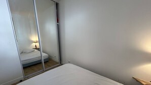 Een slaapkamer met een bed, een nachtkastje met een lamp, en een schuifdeur die leidt naar een andere kamer.