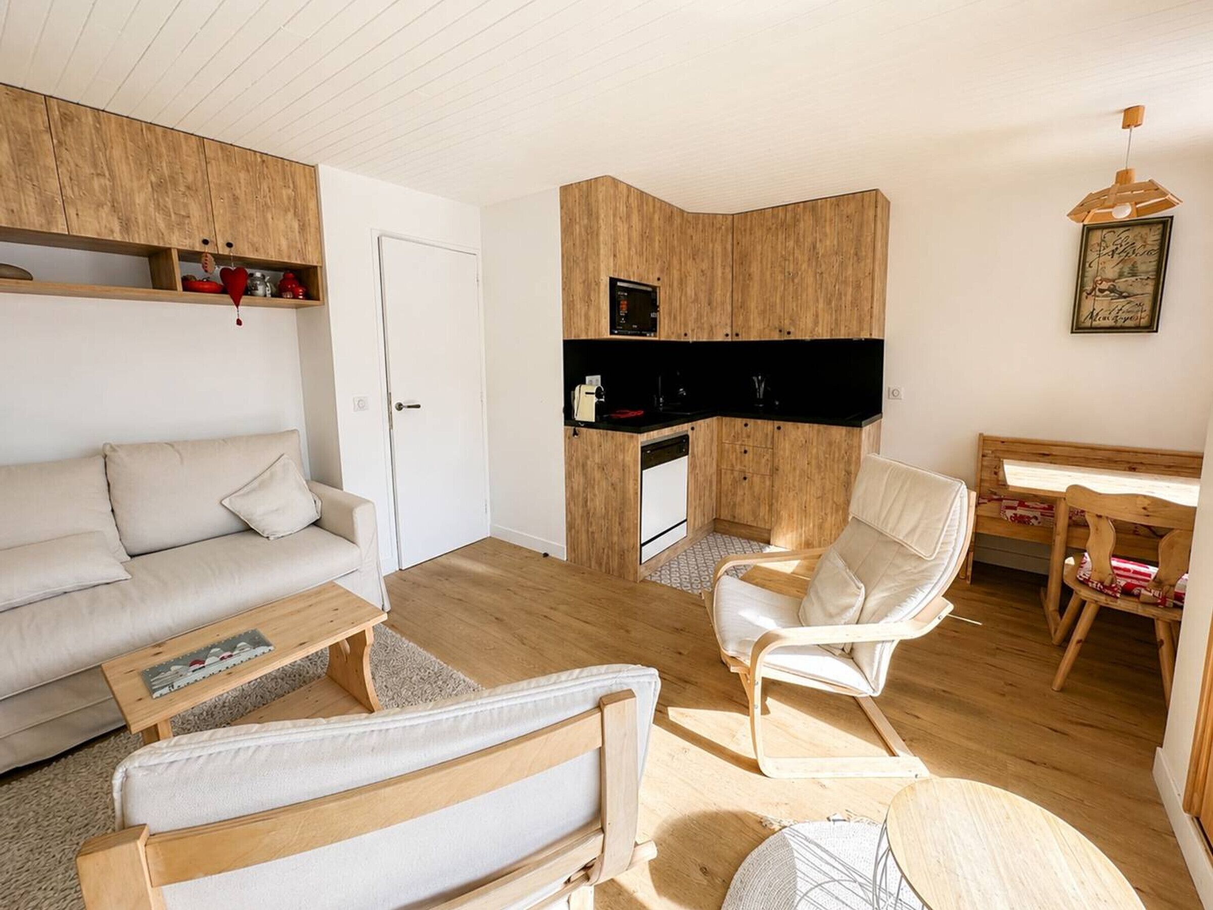 A compact living space with a sofa, a chair, a small table, and a kitchenette area.