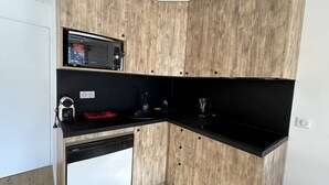 Een compacte keuken met een ingebouwde magnetron, een kleine vaatwasser en een zwart aanrecht.