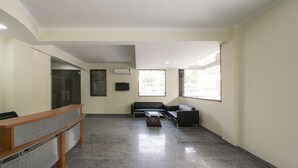 Un vestíbulo amplio con mostrador de recepción, zona de estar y ventanas grandes que dejan entrar luz natural.