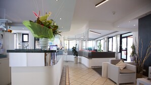 A modern reception area with a curved counter, seating, and a large potted plant.