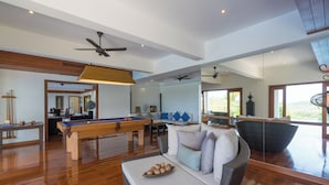 Amplia sala de estar con mesa de billar, asientos cómodos y ventanas grandes que ofrecen vistas al exterior.