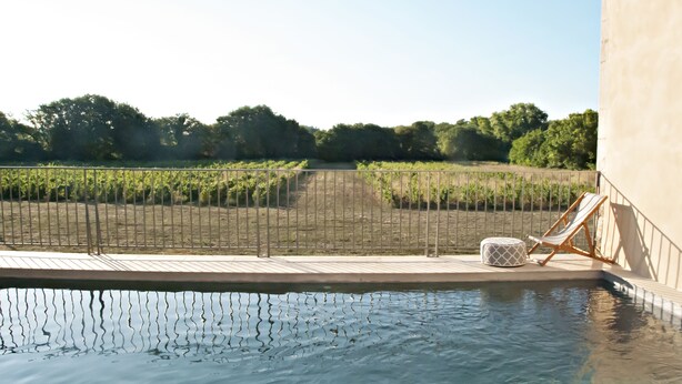 A pool area with a wooden deck, a lounge chair, and a small ottoman. - Chartreuse de Mougeres (Caux)