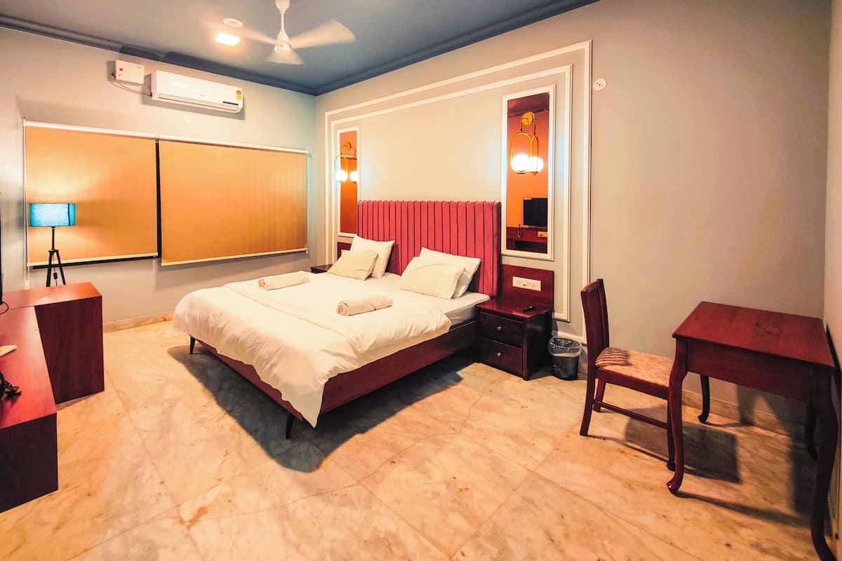 Una habitación de hotel con una cama, un escritorio, una silla, una lámpara y un ventilador de techo.