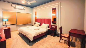A hotel room with a bed, a desk, a chair, a lamp, and a ceiling fan.