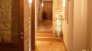 A hallway with stone walls, wooden beams, and a wooden door. - Casa Rural Fernandoegea (Ezprogui)