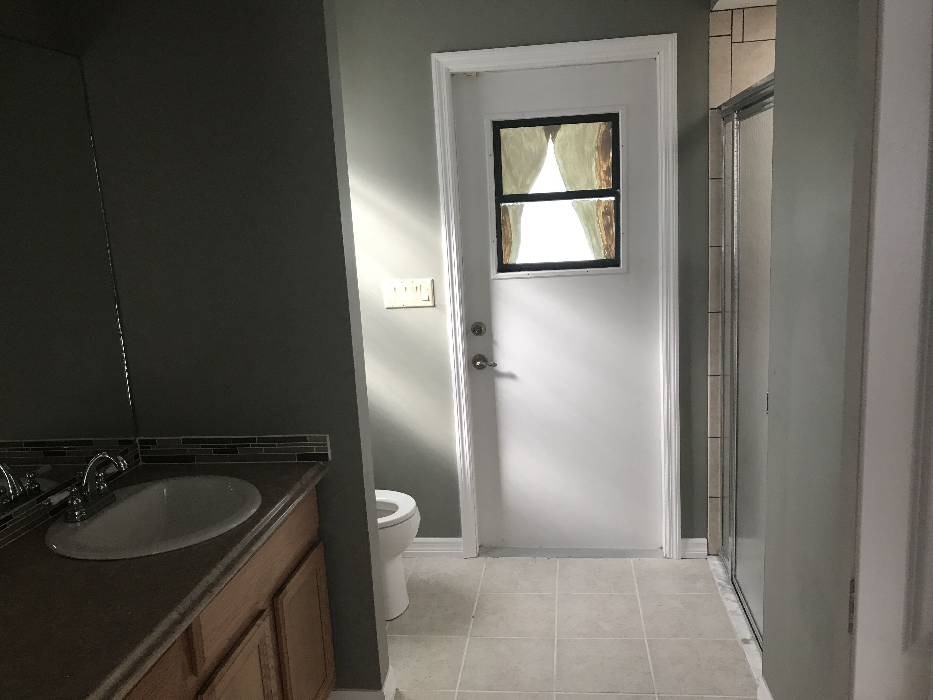 A bathroom with a sink, toilet, and a door with a window.