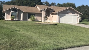 A two-story house with a garage, a front porch, and a well-maintained lawn. - 3 bedroom Pool home. Quiet Neighbourhood (Spring hill)