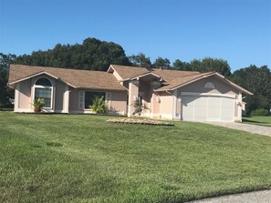 A two-story house with a garage, a front porch, and a well-maintained lawn.