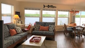 Uma sala de estar com dois sofás estampados, uma mesa de centro e uma área de jantar com mesa e cadeiras.