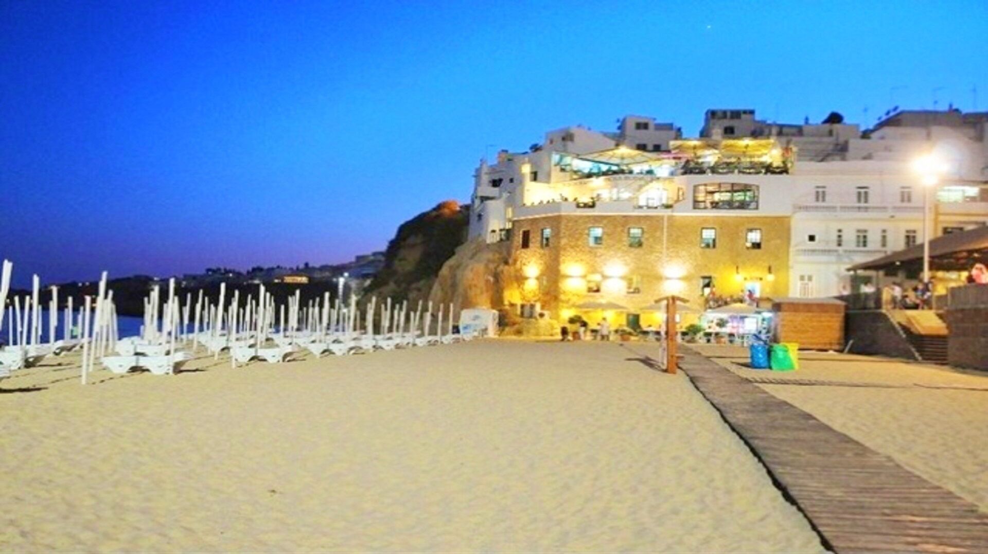 Ein Hotel direkt am Strand mit markantem Blick auf eine Klippe, einem Sandstrand und einem hölzernen Steg.