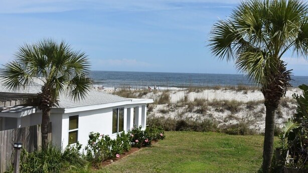 A modern house with a white exterior, a small porch, and a view of the ocean and beach.