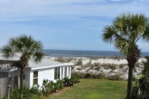 A modern house with a white exterior, a small porch, and a view of the ocean and beach. - 💲 DIRECT OCEANFRONT COTTAGE 💲 Best Section of Beach - Steps to Beach -Walk to Restaurants (St. Augustine)