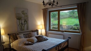 Une chambre à coucher avec un lit, des lampes de chevet, une fenêtre avec des rideaux, un radiateur et un tableau au mur.