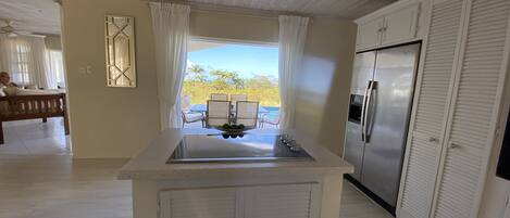 A kitchen with a central island, a refrigerator, and a view of the outdoors.