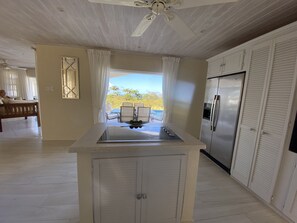 A kitchen with a central island, a refrigerator, and a view of the outdoors.
