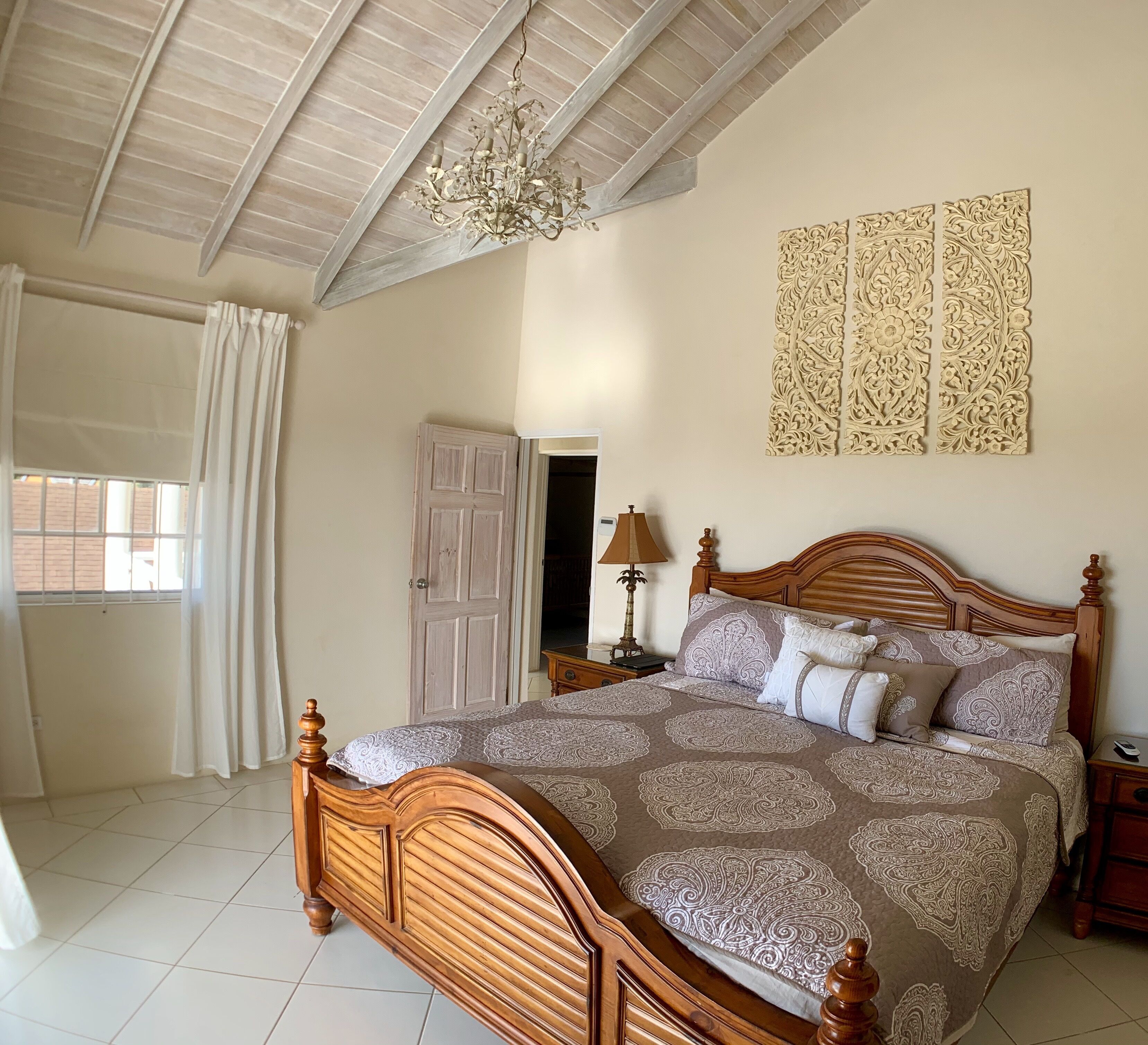Une chambre à coucher avec un lit en bois, un lustre, une table de chevet et un panneau décoratif au mur.
