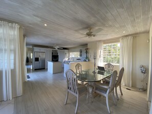 A spacious kitchen with a central island, white cabinetry, and a ceiling fan.