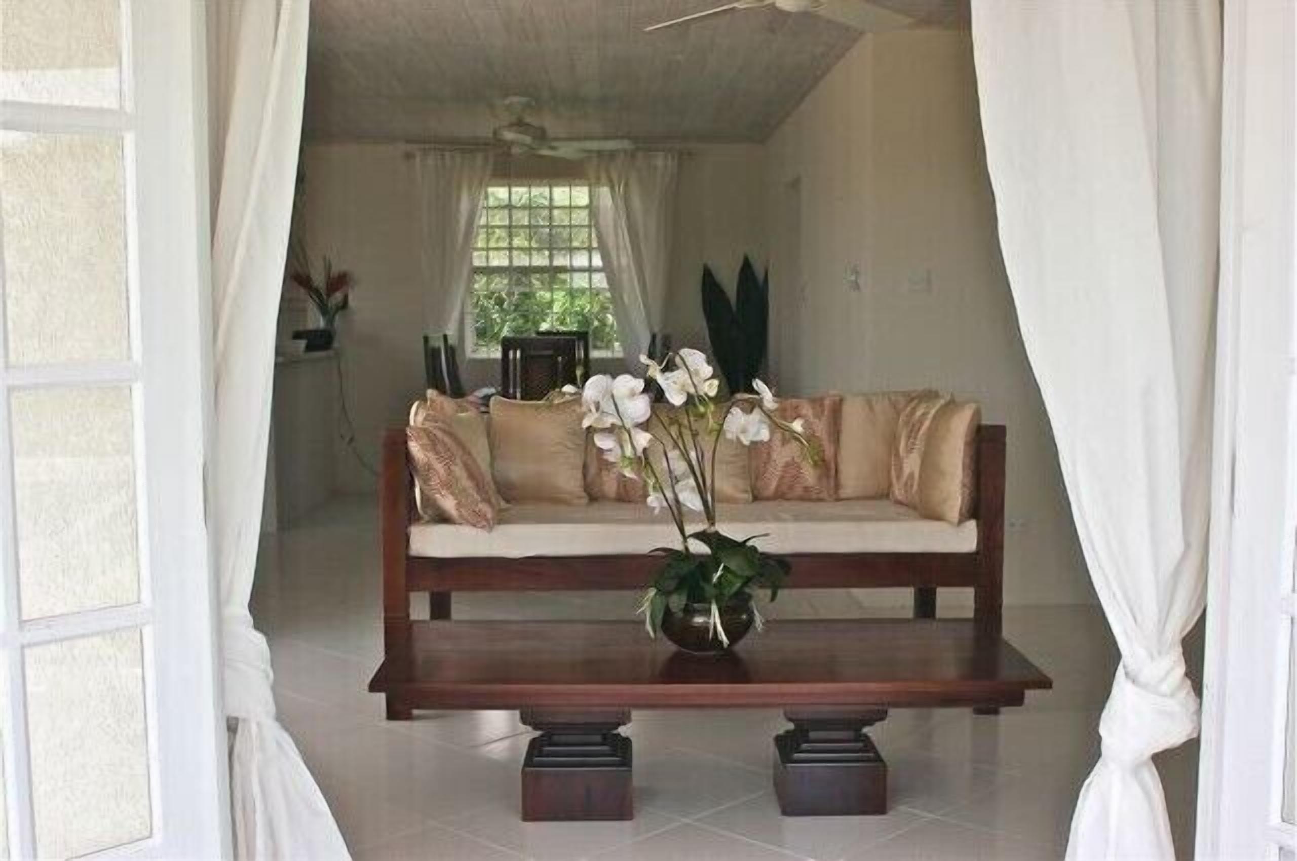 A living room with a sofa, a coffee table, and a window with curtains.