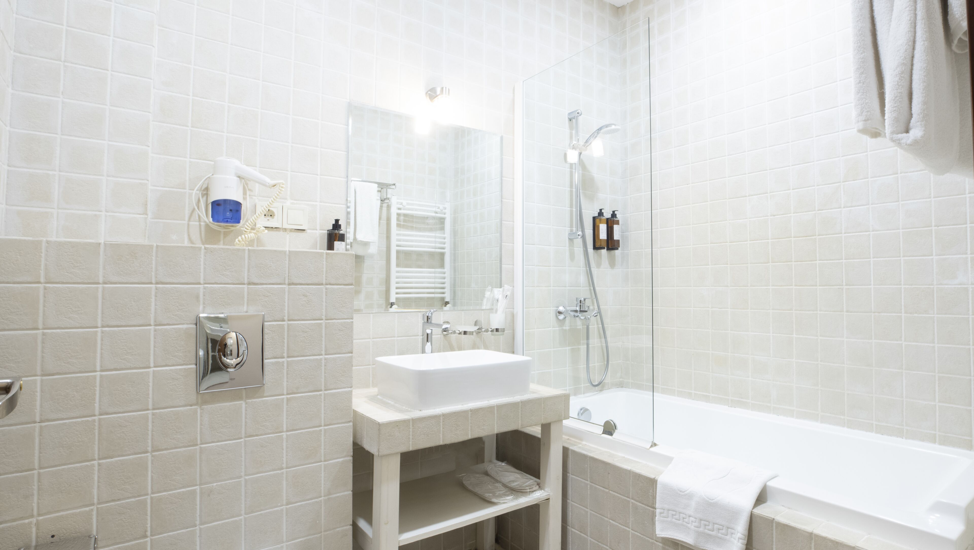 A modern bathroom with a white sink, mirror, and shower.